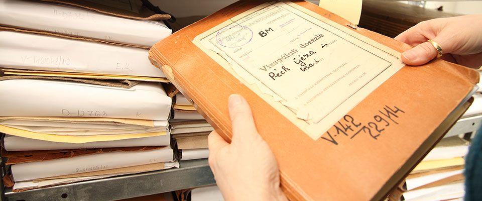 Архивное дело из Исторического архива спецслужб Венгрии (Állambiztonsági Szolgálatok Történeti Levéltára – ÁBTL), в руках держат папку с надписью «Vizsgálati dosszié» (следственное дело)